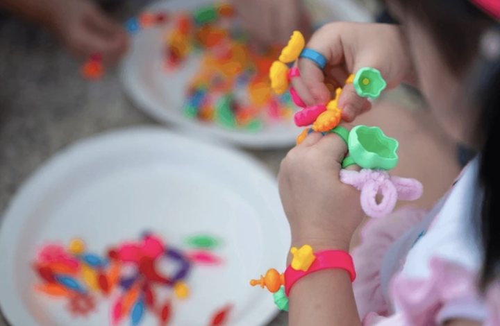 A child's hands working on a craft project at a table.