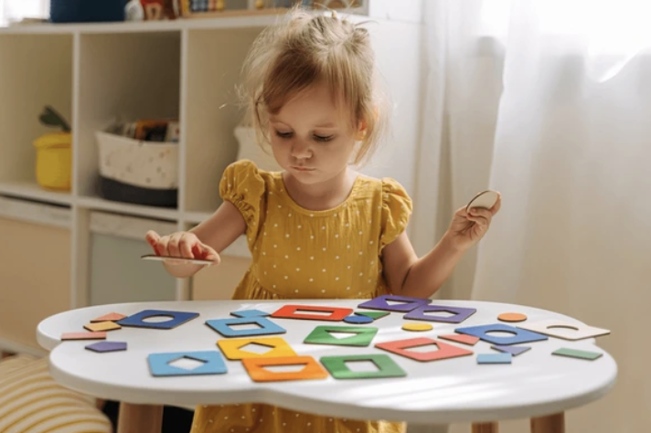 A preschool-age child sorting colored shapes at a table.