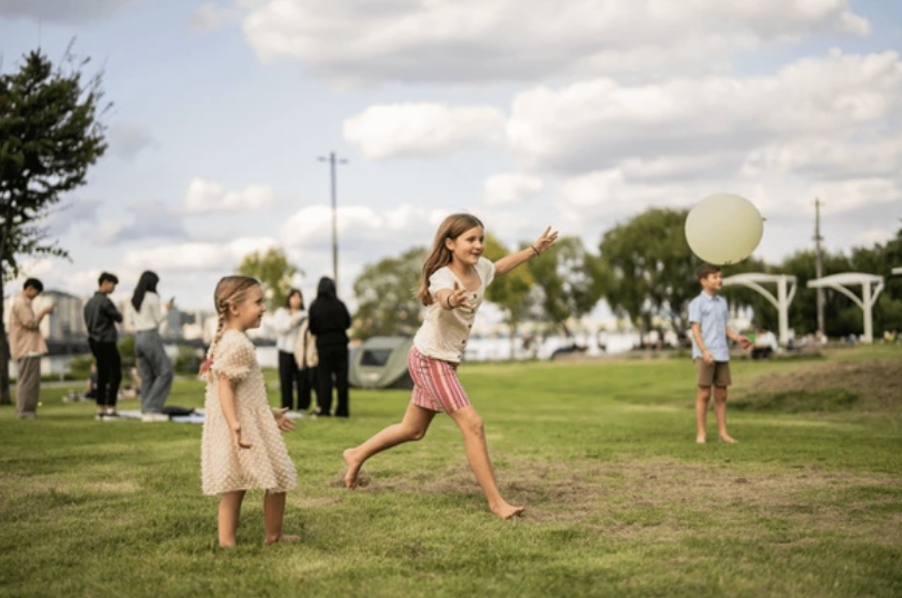 Children playing with a white ball outdoors, barefoot on grass.
